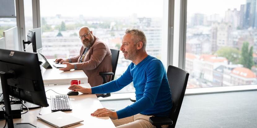 twee personen achter computer aan een bureau